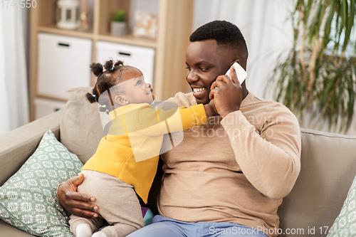 Image of father with baby at home calling on smartphone