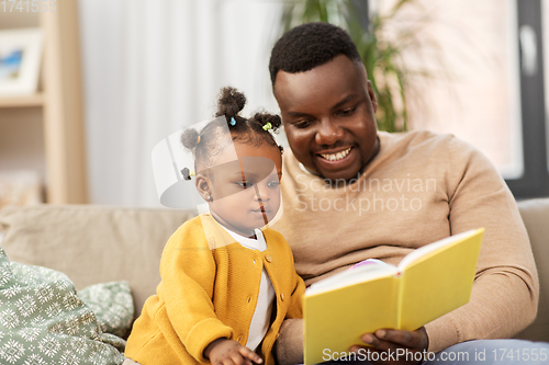 Image of african father reading book for baby daughter