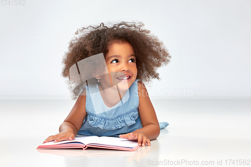 Image of smiling little african american girl reading book