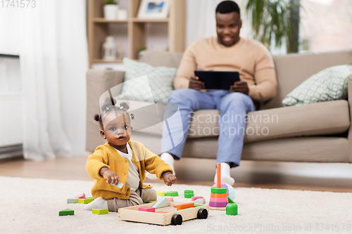 Image of african baby girl playing with toy blocks at home