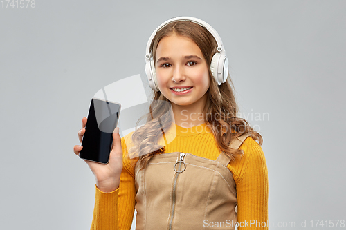 Image of teenage girl in headphones showing smartphone