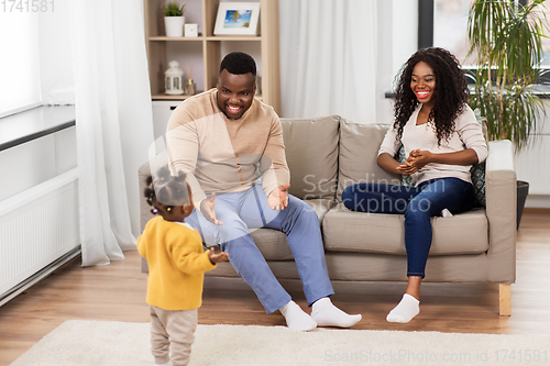 Image of african family playing with baby daughter at home