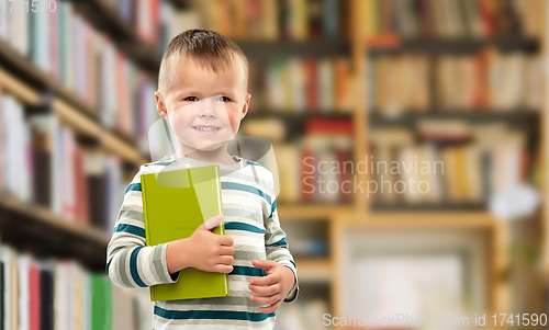 Image of portrait of smiling boy holding book over library