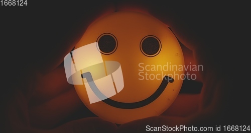 Image of Hands holding glowing smiley head closeup footage