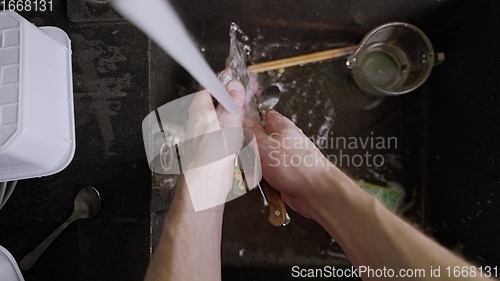 Image of Washing dirty dishware in black sink