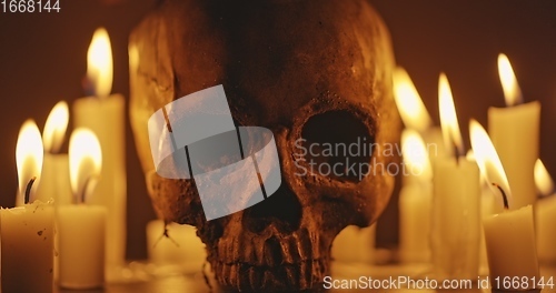 Image of Candles and human skull in darkness closeup footage