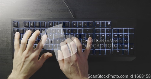 Image of Close-up of typing male hands on illuminated keyboard