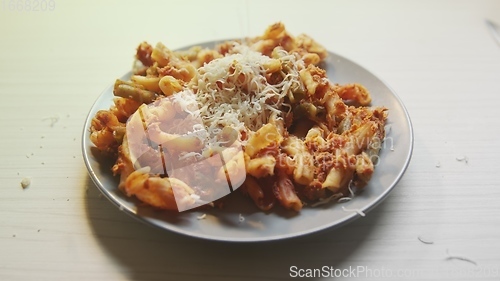 Image of Cheese topping beiing applied to bowl of pasta