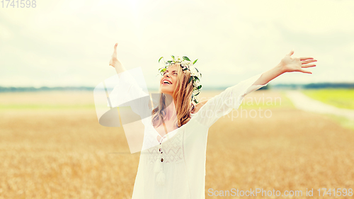 Image of happy young woman in flower wreath on cereal field