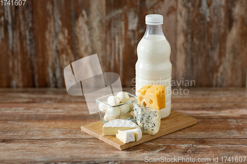 Image of different kinds of cheese and milk on wooden board