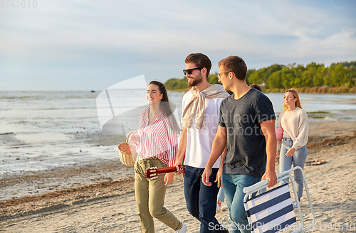 Image of happy friends walking along summer beach