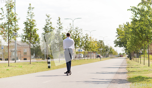 Image of young businessman riding electric scooter outdoors