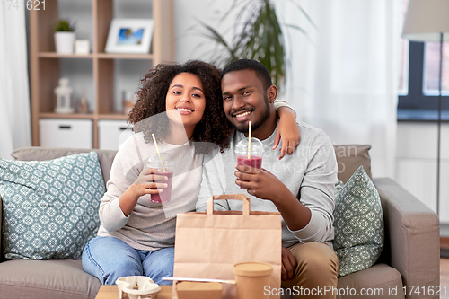 Image of happy couple with takeaway food and drinks at home