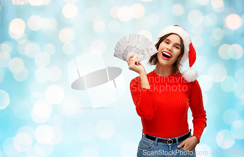 Image of happy woman in santa hat with money on christmas