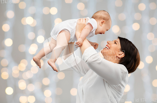 Image of happy middle-aged mother with baby over lights