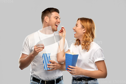 Image of happy couple in white t-shirts eating popcorn