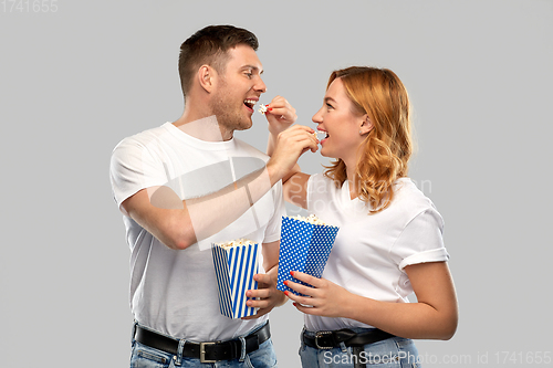 Image of happy couple in white t-shirts eating popcorn