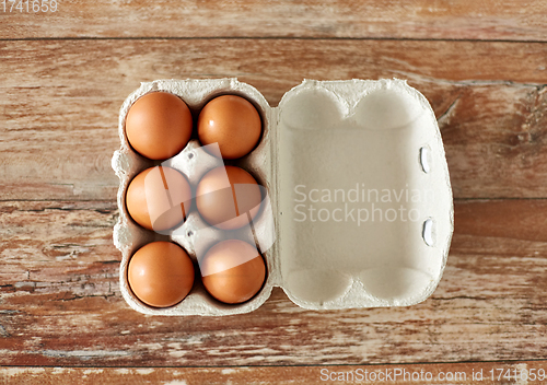 Image of close up of eggs in cardboard box on wooden table