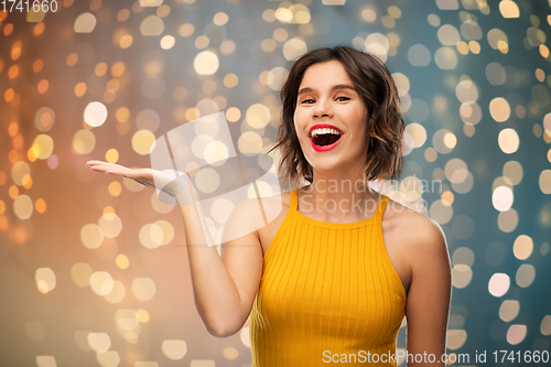 Image of happy young woman holding something on empty hand