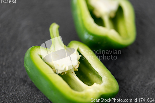 Image of cut green pepper on slate stone background