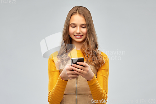 Image of smiling teenage girl using smartphone