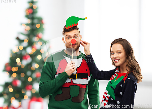 Image of couple with christmas party props in ugly sweaters