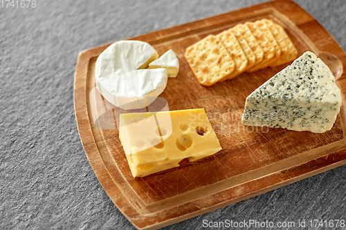 Image of different cheeses and crackers on wooden board