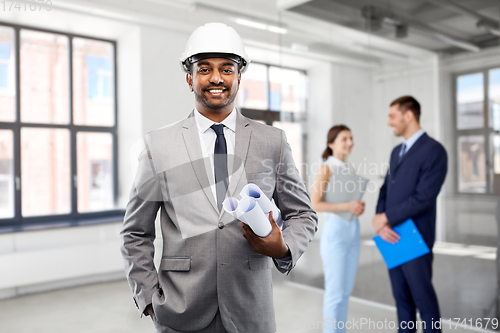 Image of indian male architect in helmet with blueprints