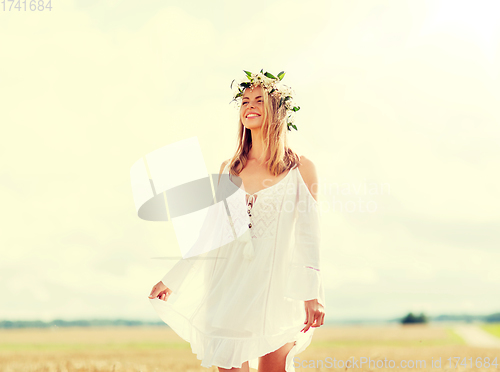 Image of happy young woman in flower wreath on cereal field