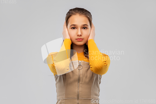 Image of smiling teenage girl closing ears by hands