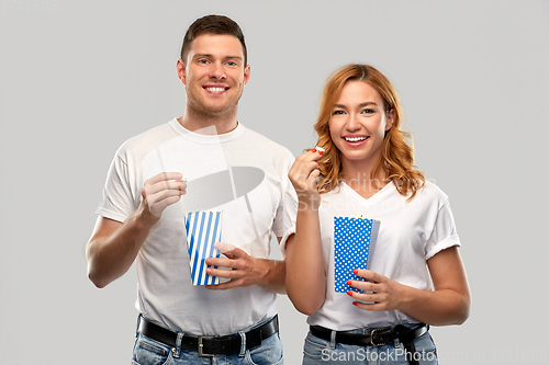 Image of happy couple in white t-shirts eating popcorn