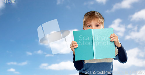 Image of little boy hiding over book over sky