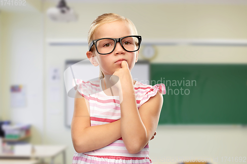 Image of cute little girl in black glasses thinking