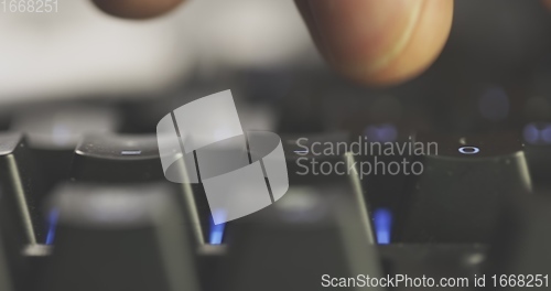 Image of Close-up of typing male hands on illuminated keyboard