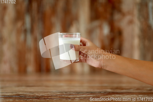 Image of close up of female hand holding glass of milk