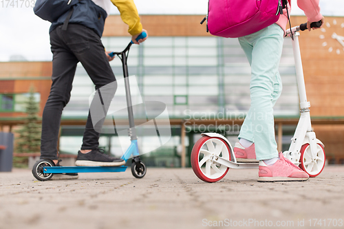 Image of school children with backpacks and scooters