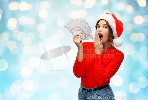 Image of surprised woman in santa hat with money