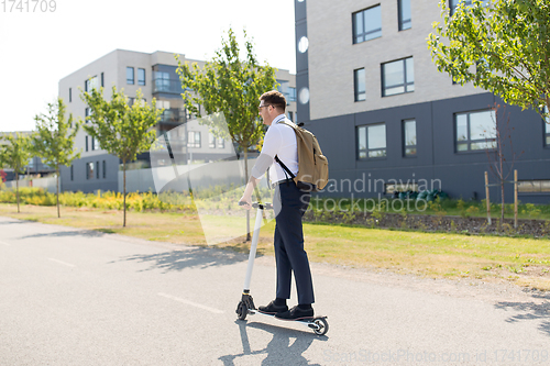 Image of businessman with backpack riding electric scooter