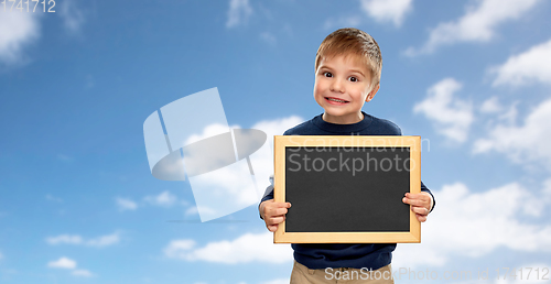 Image of little boy with black blank chalkboard over sky