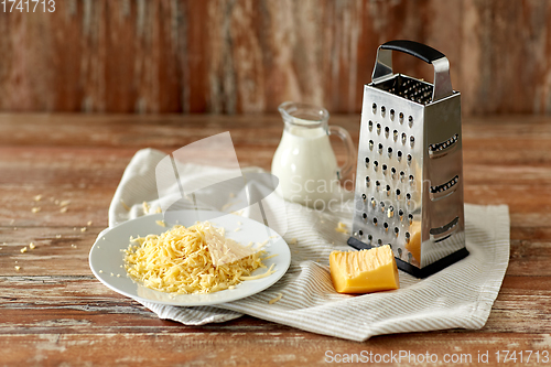 Image of close up of grated cheese and jug of milk on table