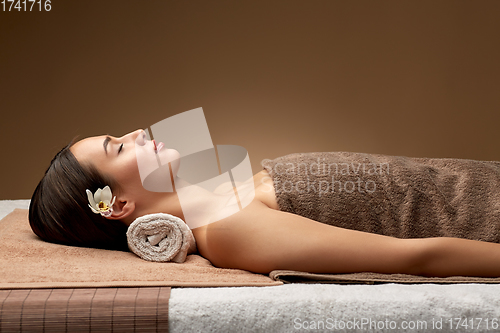 Image of young woman lying at spa or massage parlor