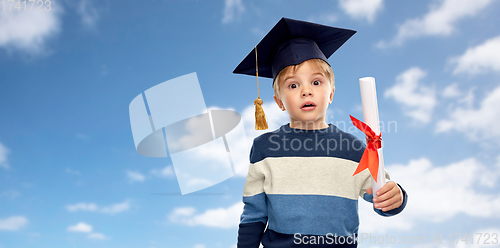 Image of little boy in mortarboard with diploma over sky