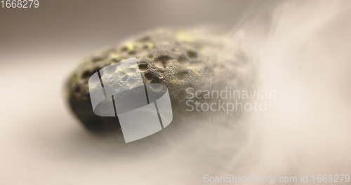 Image of Smoke whirling around small meteorite stone