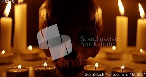 Image of Candles and human skull in darkness closeup footage