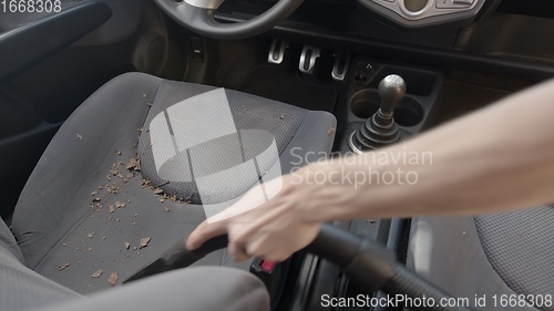 Image of Man cleaning dirty car interior with vacuum cleaner