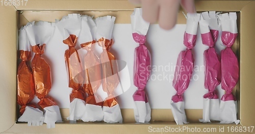 Image of Man and woman picking out christmas chocolate from box