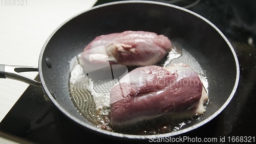 Image of Roast duck breast in frying pen closeup footage