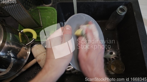 Image of Washing dirty dishware in black sink