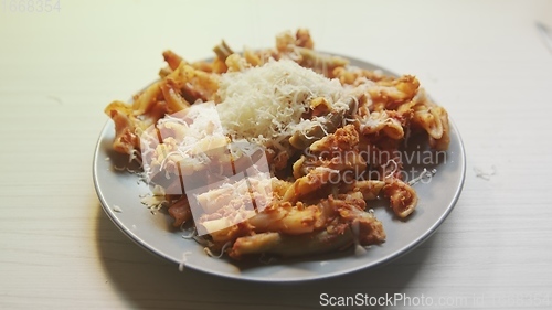 Image of Cheese topping beiing applied to bowl of pasta