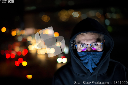 Image of hacker using laptop computer while working in dark office